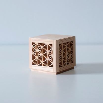 An unlit kumiko light fixture, revealing the intricate wooden latticework and the natural grain of the wood.