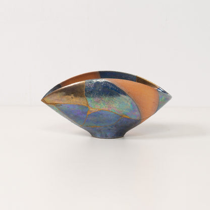 A unique asymmetric kintsugi bowl stands alone highlighting the colorful glazes of kintsugi pottery
