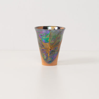 An authentic kintsugi cup stands alone highlighting colorful metallic glazes that define this beautiful kintsugi pottery