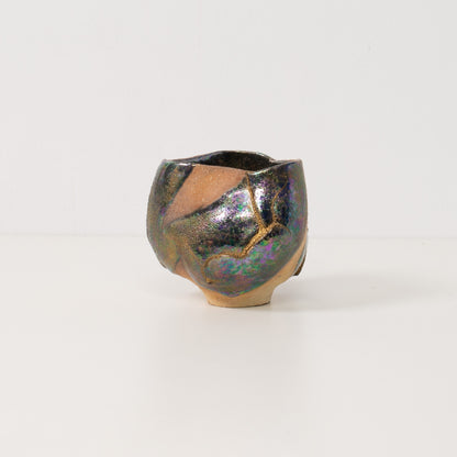 A wide iridescent kintsugi matcha bowl stands alone highlighting vibrant metallic tones that define kintsugi pottery art