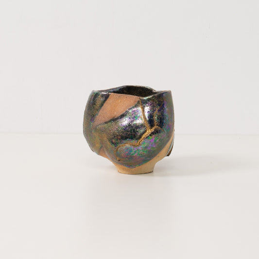 A wide iridescent kintsugi matcha bowl stands alone highlighting vibrant metallic tones that define kintsugi pottery art