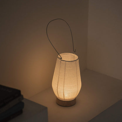 Overhead view of a lit portable lamp made of mino washi paper highlighting the ribbed structure and warm light