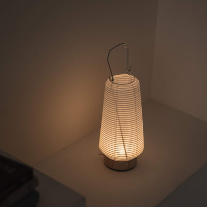 Overhead view of a lit portable lamp made of mino washi paper highlighting the ribbed structure and warm light