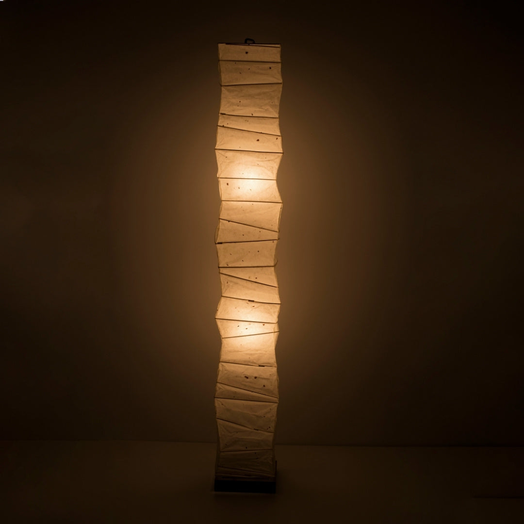 A tall, Japanese washi paper floor lamp emitting a warm glow.