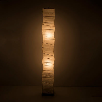 A tall, Japanese washi paper floor lamp emitting a warm glow.