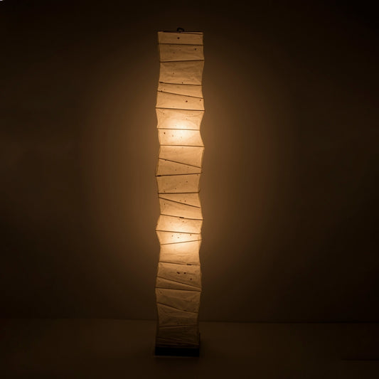 A tall, Japanese washi paper floor lamp emitting a warm glow.
