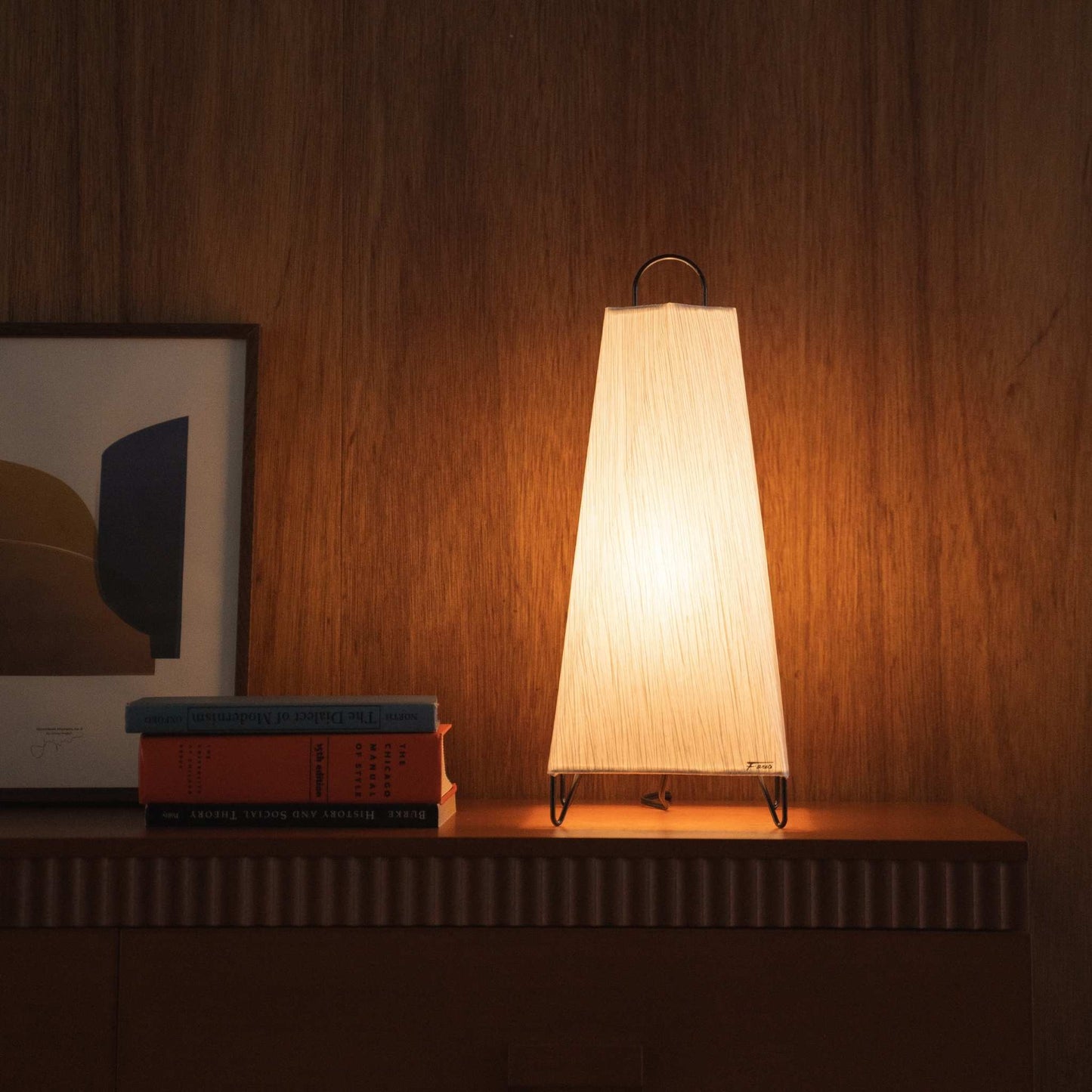Lit Japanese paper floor lamp ORI small glowing on a mid-century modern wooden console table as a beautiful accent lamp.