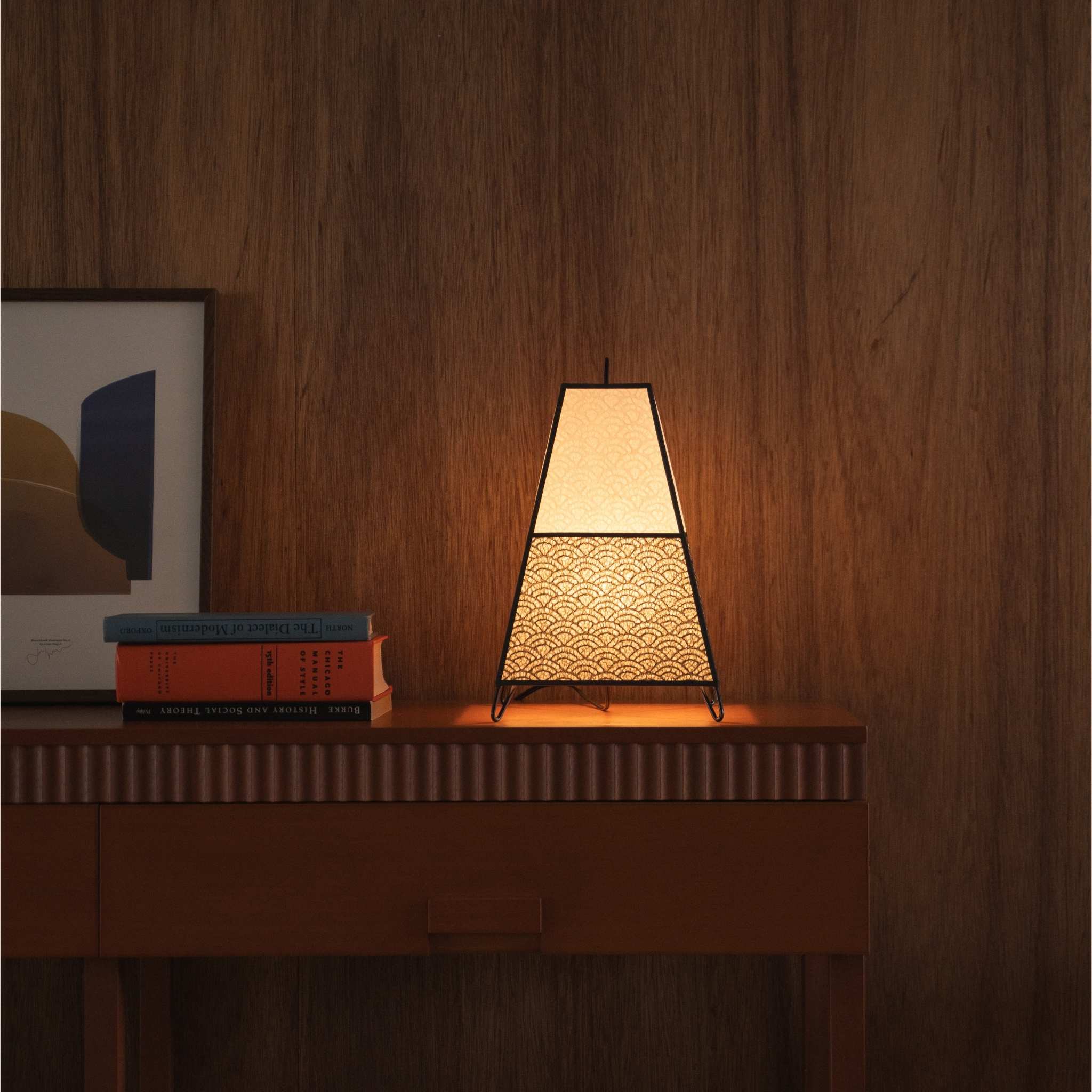 Glowing Japanese paper lamp KURA small resting on a mid-century modern wooden console table as a cozy accent lamp.