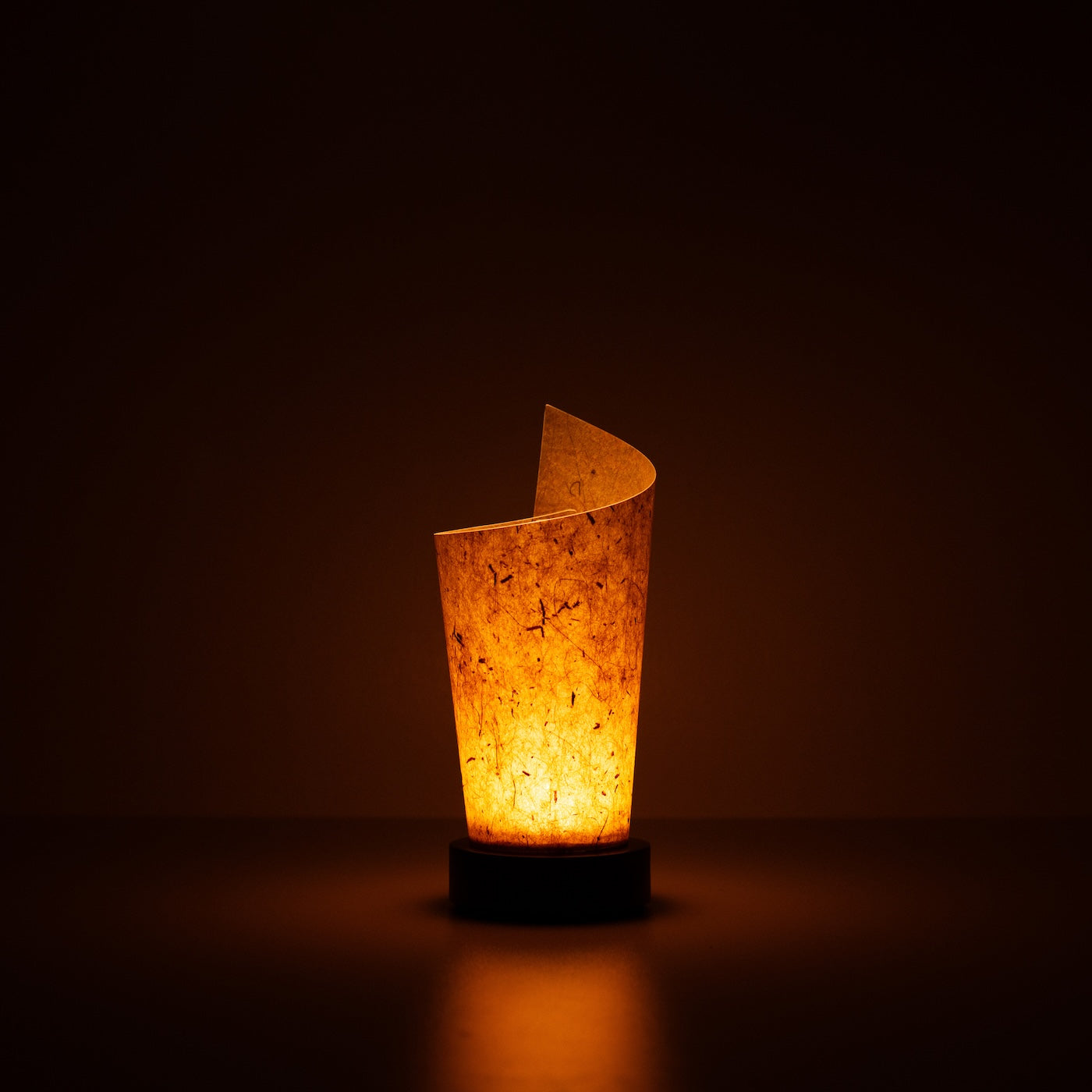 Japanese Paper Table Lamp "Maki" Cedar Bark, brown, Mino Washi paper - lit paper lamp casting a warm glow with visible rustic flecks.