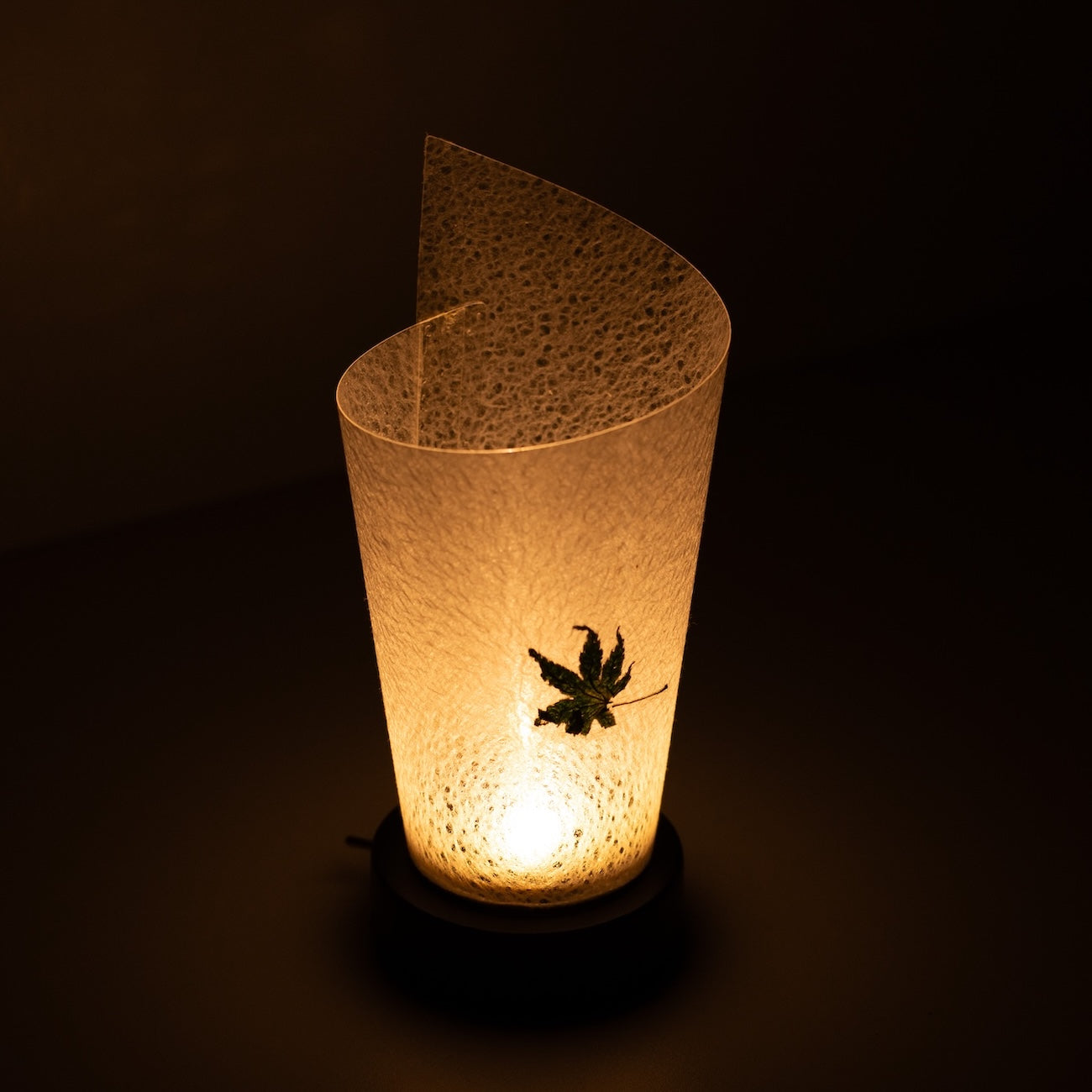 Japanese Paper Table Lamp "Maki" Momiji Leaf, white, Mino Washi paper - high angle view of lit Japandi lamp showing rolled design.