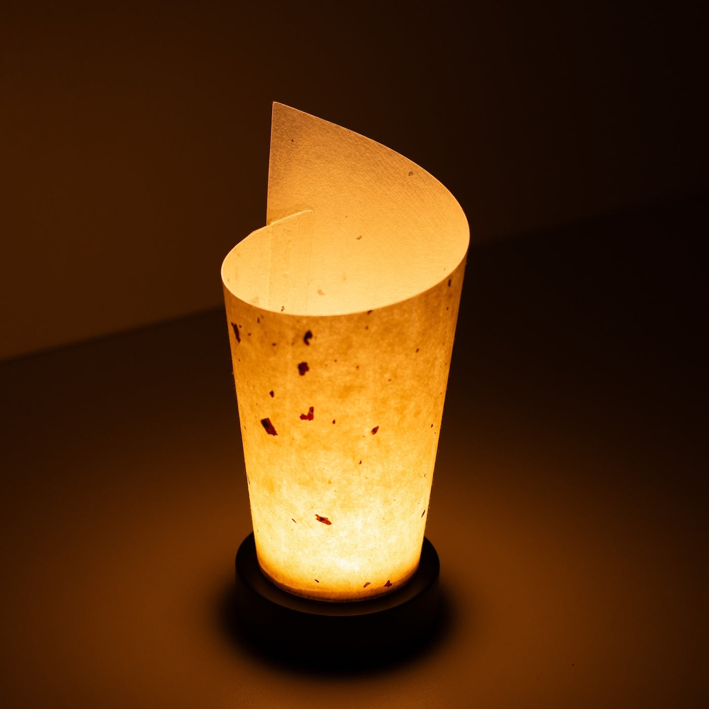 Japanese Paper Table Lamp "Maki", natural, Mino Washi paper - high angle view of lit Japandi lamp showing rolled design.