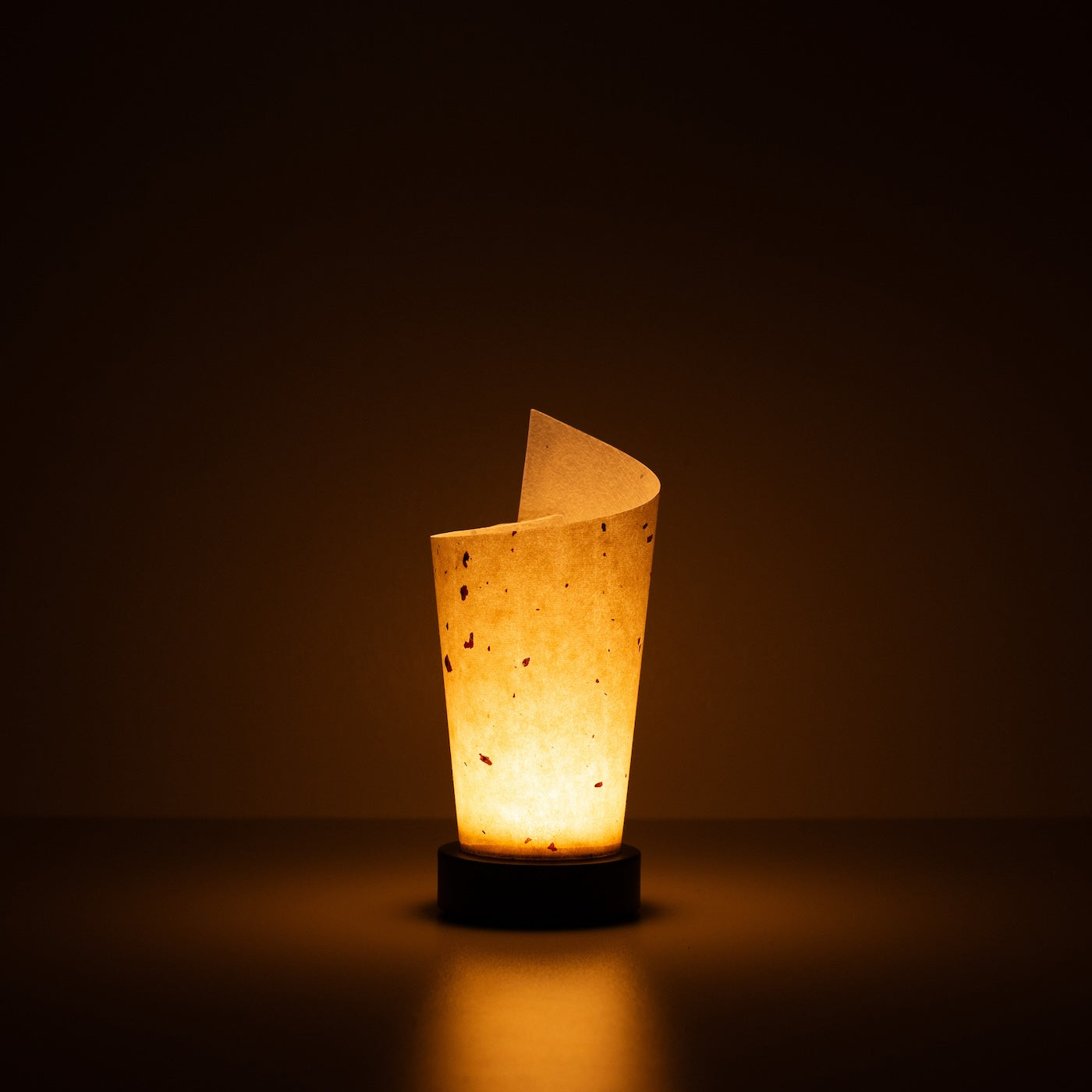 Japanese Paper Table Lamp "Maki", natural, Mino Washi paper - lit paper lamp casting a warm glow with visible rustic flecks.