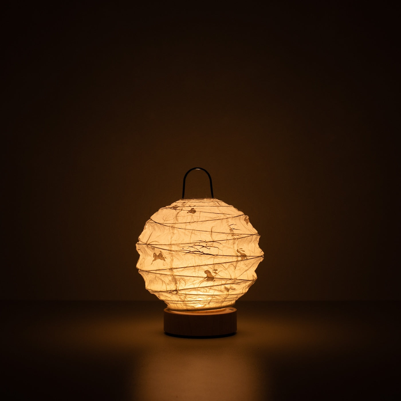 Japanese Paper Table Lamp "Yuhi" Rabbit, white, Mino Washi paper - lit round paper lamp casting a warm glow in a dark room.