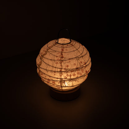 Japanese Paper Table Lamp "Yuhi" Sakura, white, Mino Washi paper - high angle view of lit Japandi style lamp with wire handle.