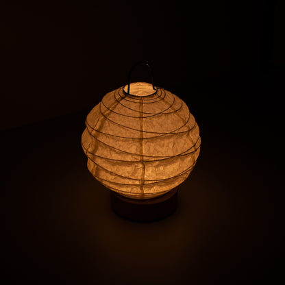 Japanese Paper Table Lamp "Yuhi", white, Mino Washi paper - high angle view of lit Japandi style lamp with wire handle.
