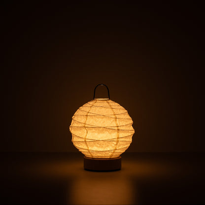 Japanese Paper Table Lamp "Yuhi", white, Mino Washi paper - lit round paper lamp casting a warm glow in a dark room.