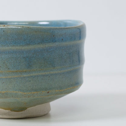 Close-up detail of "Summer Sky" matcha chawan bowl showing the translucent blue glaze revealing warm earthen brown clay ridges.