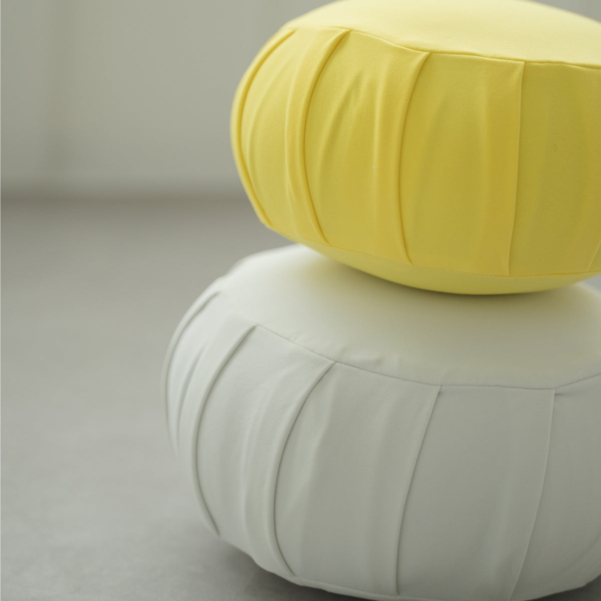 Mimosa yellow and moonlight white Japanese meditation cushion zafu, arranged in a bright room for daily mindfulness.
