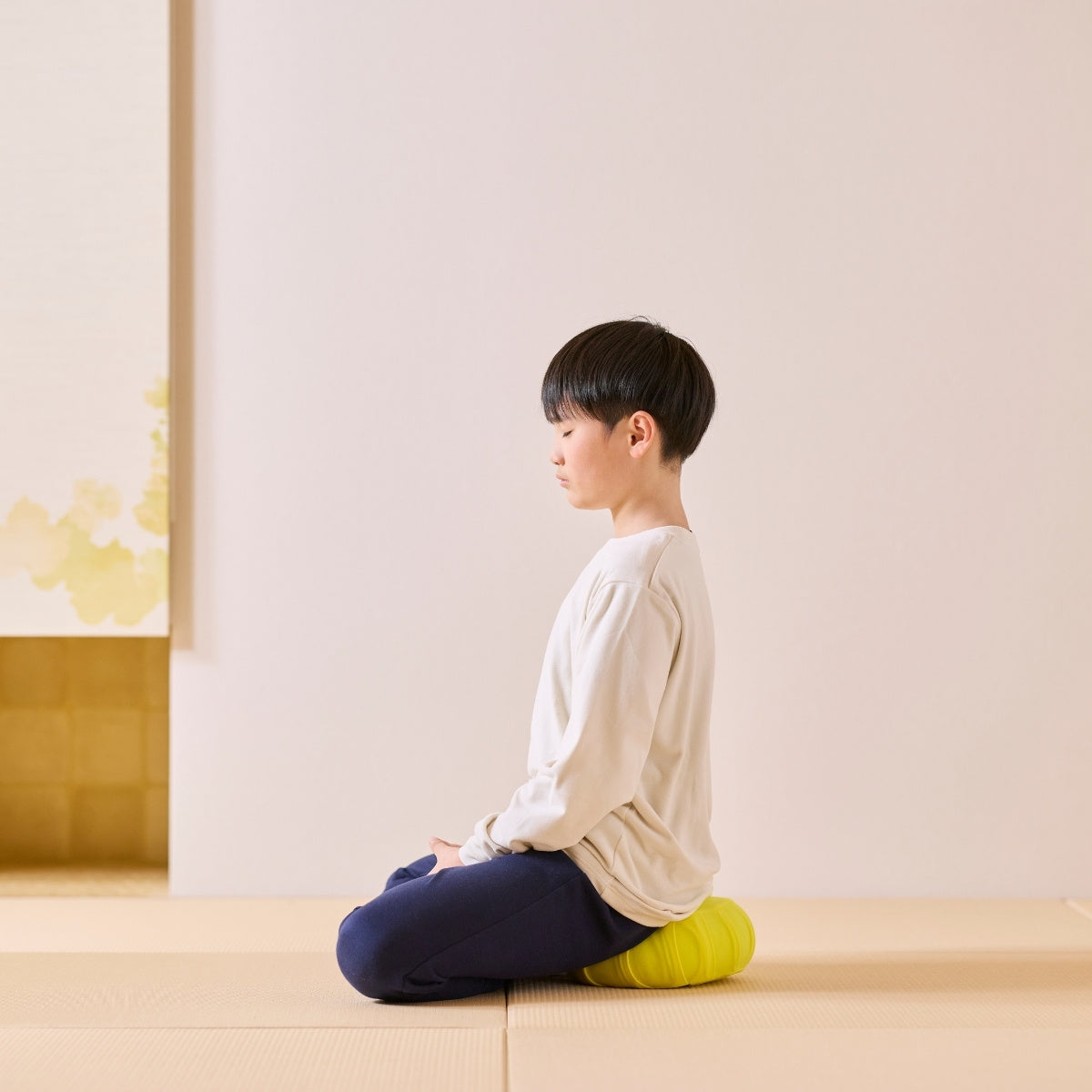 Mimosa yellow Japanese meditation cushion zafu, used by a child on a tatami mat practicing a daily mindfulness routine.