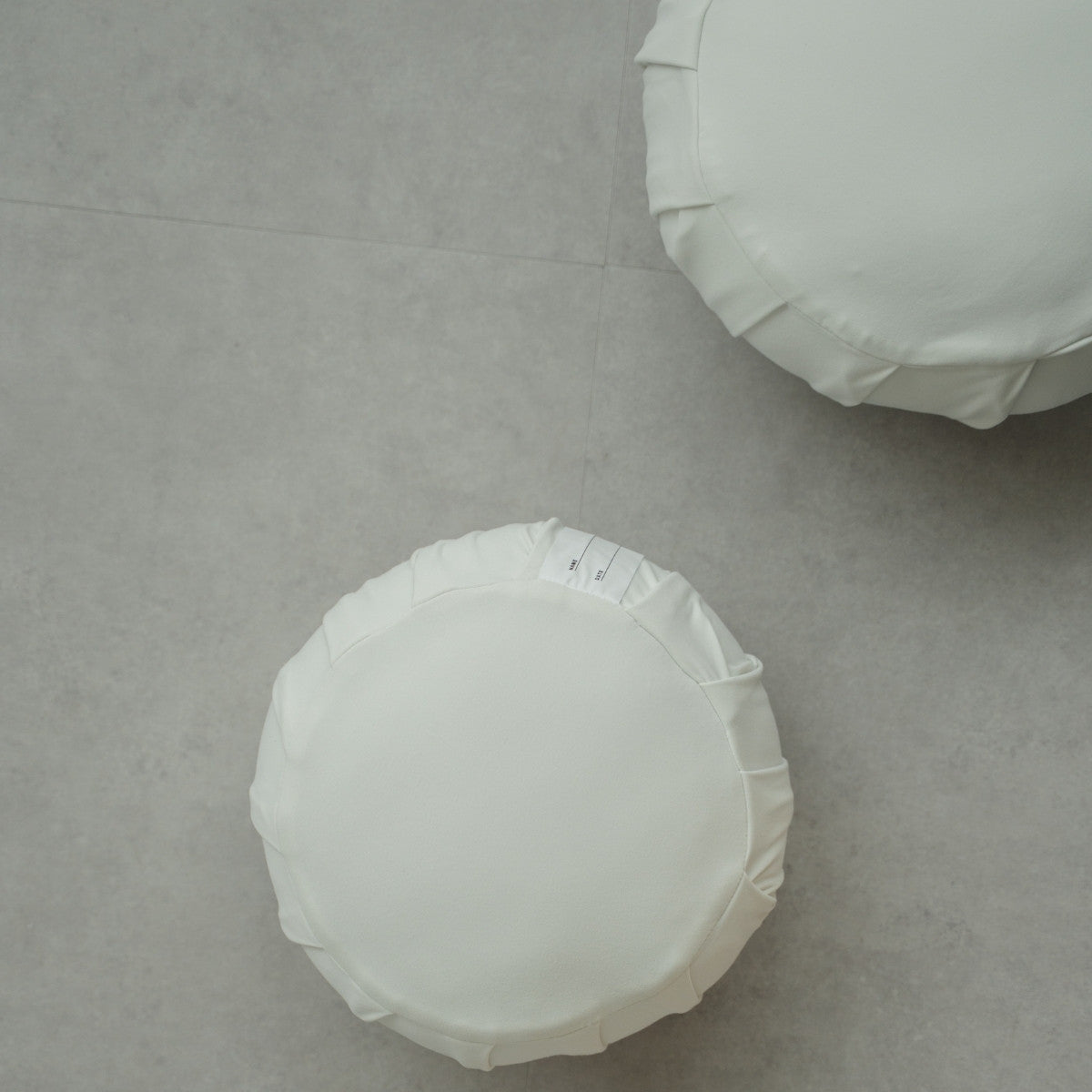 Two moonlight white Japanese meditation cushions (zafu) on a modern grey floor, ready for a family mindfulness routine.