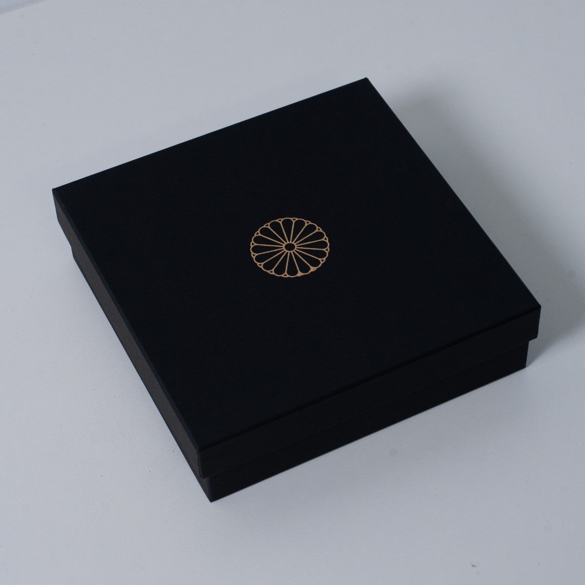 Closed slim black Ninshu's gift box for Japanese incense holder pottery, featuring a gold imperial chrysanthemum crest on the lid.
