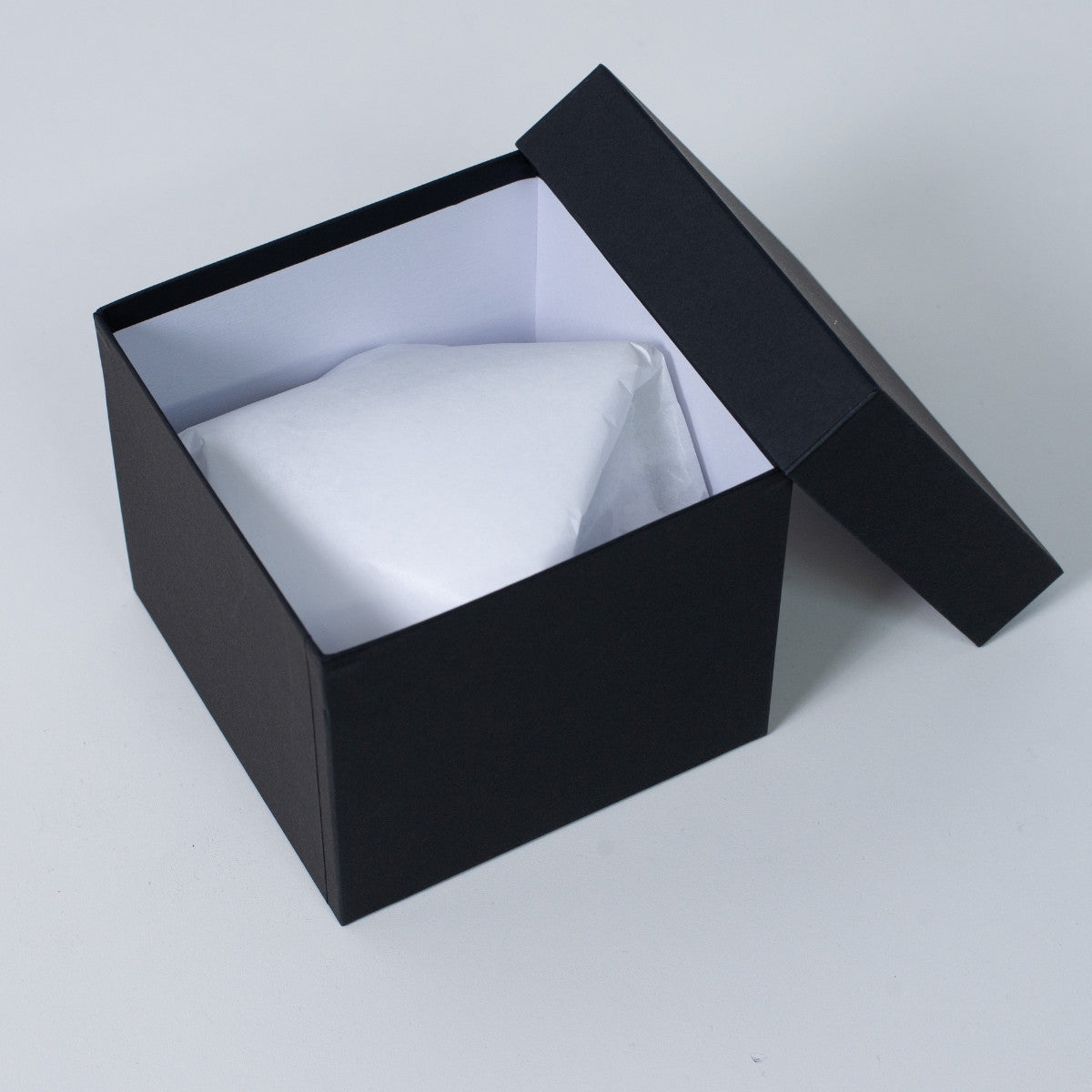 Open black square Ninshu's gift box for Japanese pottery, showing a securely wrapped vessel inside white packaging paper.
