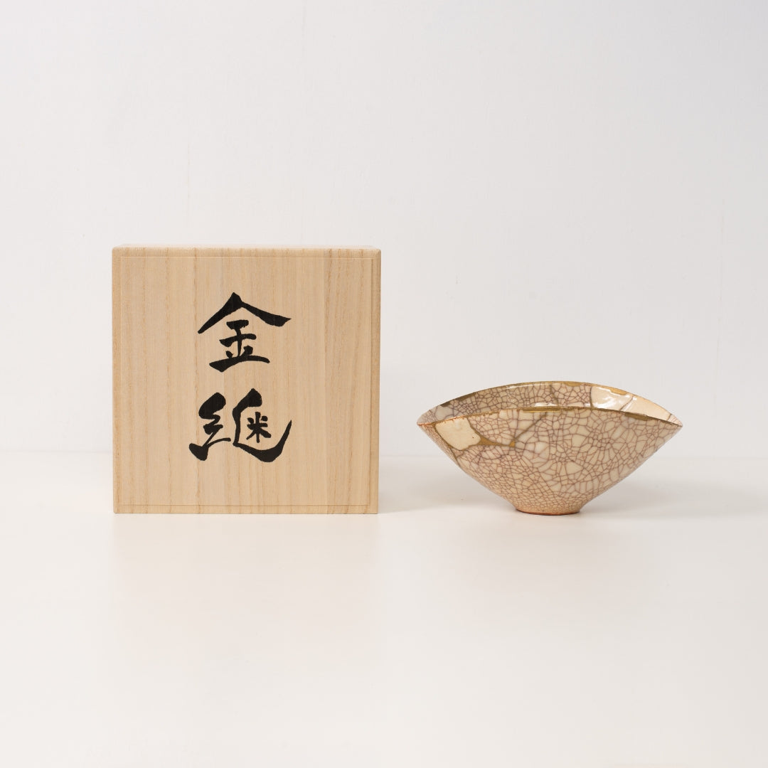 A white kintsugi bowl rests beside a wooden box representing beautiful wabi sabi art and resilient kintsugi pottery