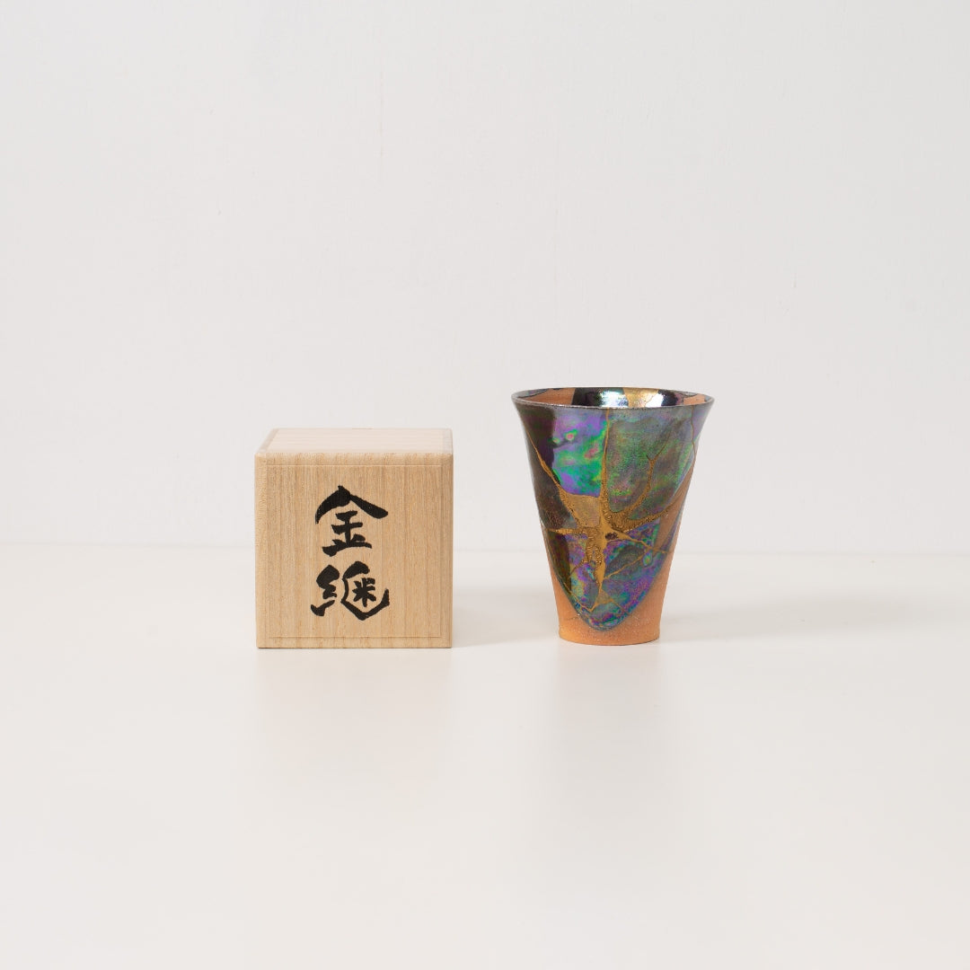A wide iridescent kintsugi cup rests beside a wooden box ready to be given as a unique japanese gift of wabi sabi art