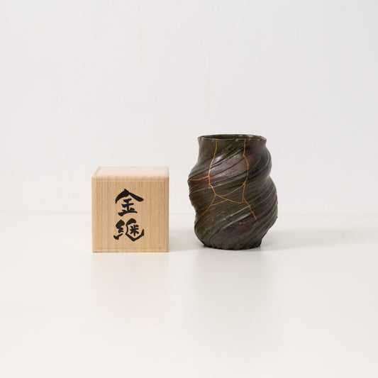 A dark kintsugi flower vase sits next to a wooden box representing beautiful wabi sabi art and a unique japanese gift