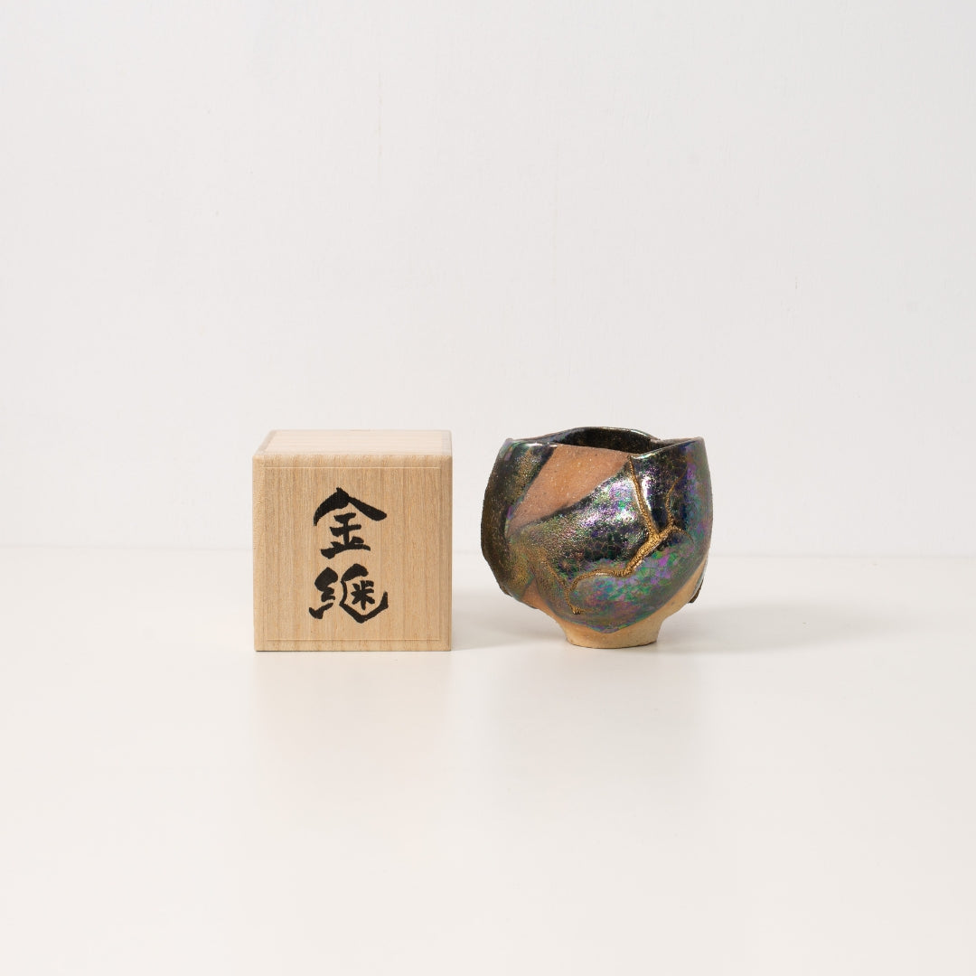 A wider iridescent kintsugi matcha bowl rests next to a wooden box ready to be given as a unique japanese gift
