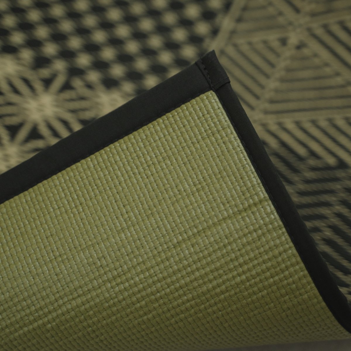 Corner of the Japanese Tatami Yoga Mattress "Ed Plain" Black lifted to show the textured PVC backing and black border.