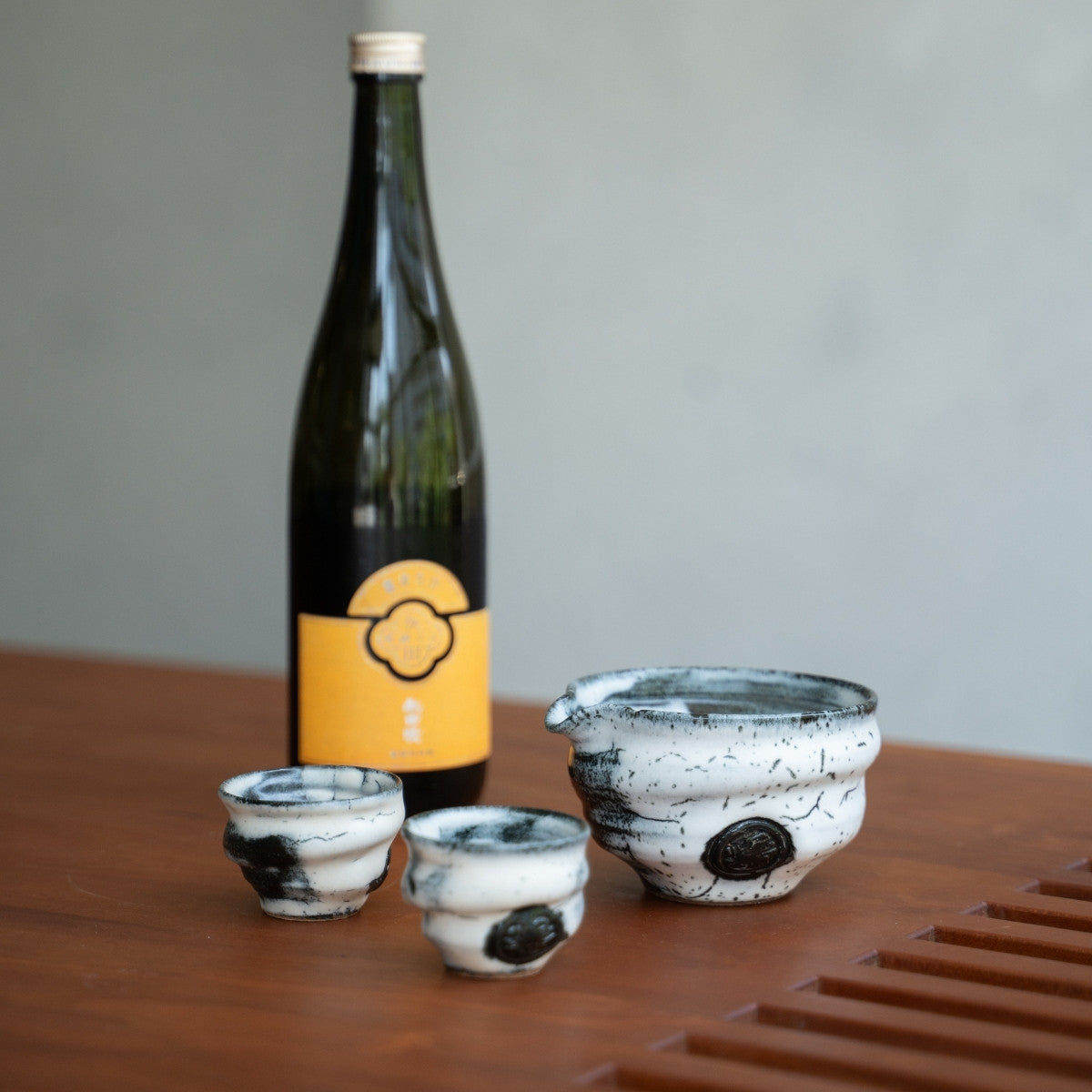 Kreatives japanisches Sake-Set aus Kristallglas mit Karaffe und Bechern neben einer Sake-Flasche, ideal als Premium-Geschenk für Sake-Liebhaber