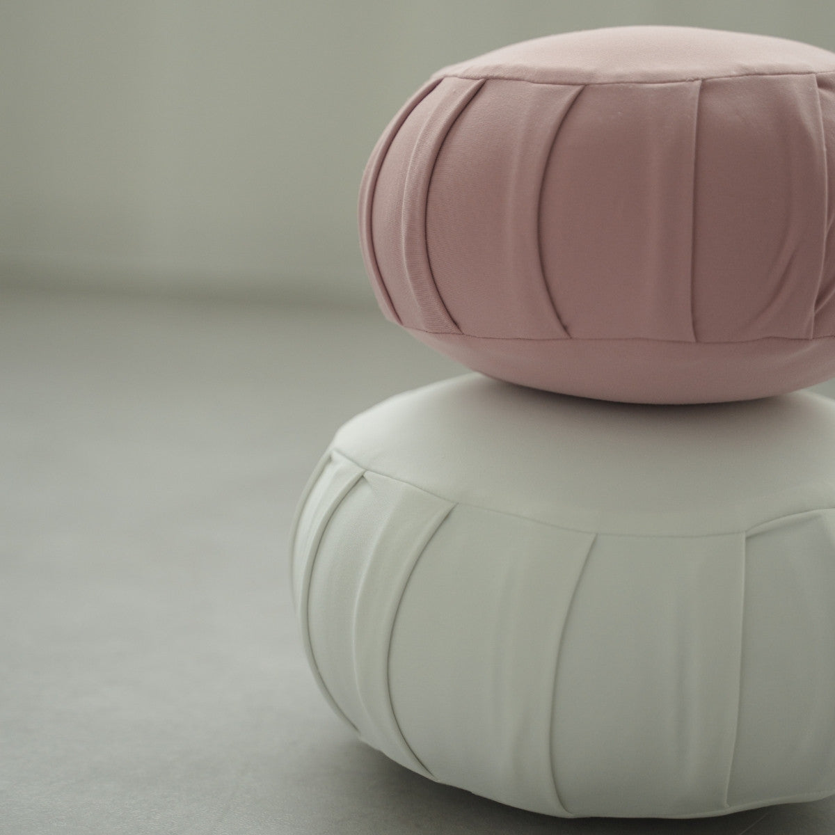 Rose and moonlight white Japanese meditation cushion zafu, placed on a grey floor preparing for a family zen routine.