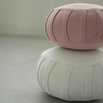 Rose and moonlight white Japanese meditation cushion zafu, placed on a grey floor preparing for a family zen routine.
