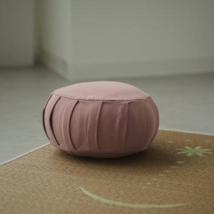 Rose Japanese meditation cushion zafu, placed on a woven mat in a calm room for a daily zen ritual.
