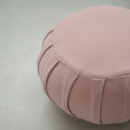 Close-up of a rose Japanese meditation cushion (zafu) showing fabric details on a modern floor for relaxing home yoga.