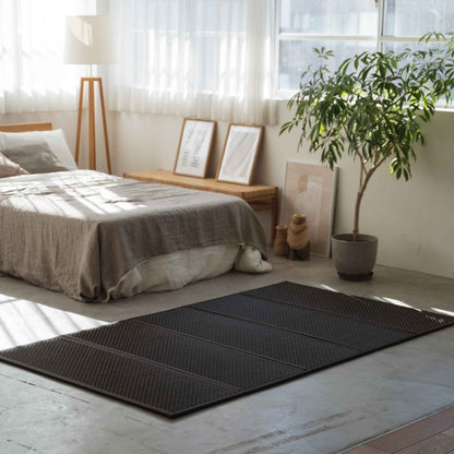 Black semi-double tatami mat on a concrete bedroom floor providing a modern zen foundation for a futon.