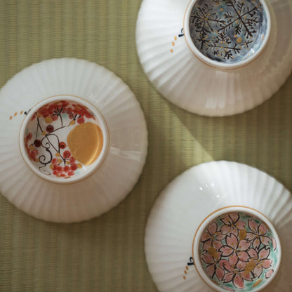 Three upside down japanese matcha bowls on a tatami mat showing moon snow and flower designs on their bases.