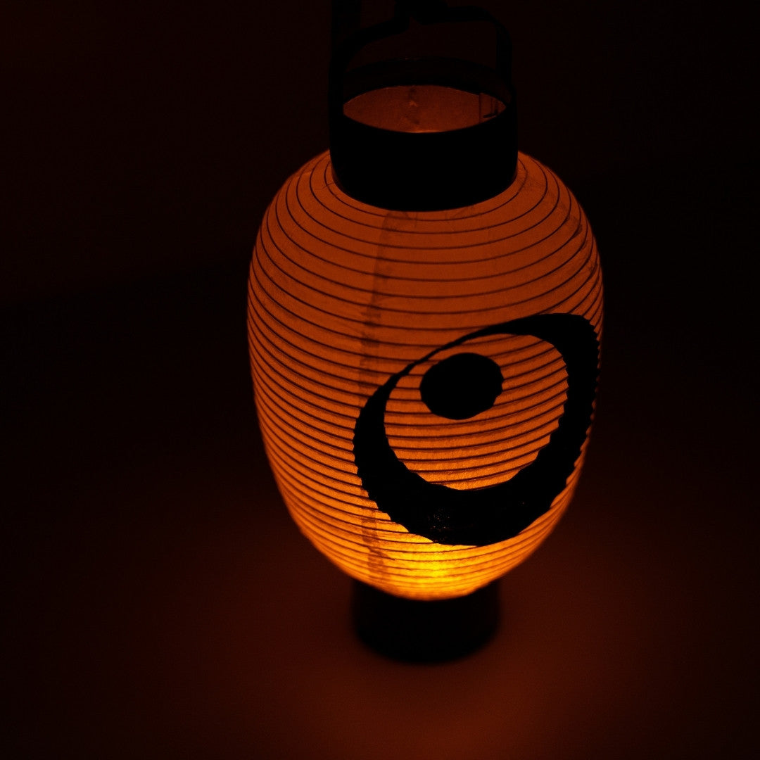 High-angle shot of a glowing moon and star japanese lantern showing the bamboo bow structure and warm light.
