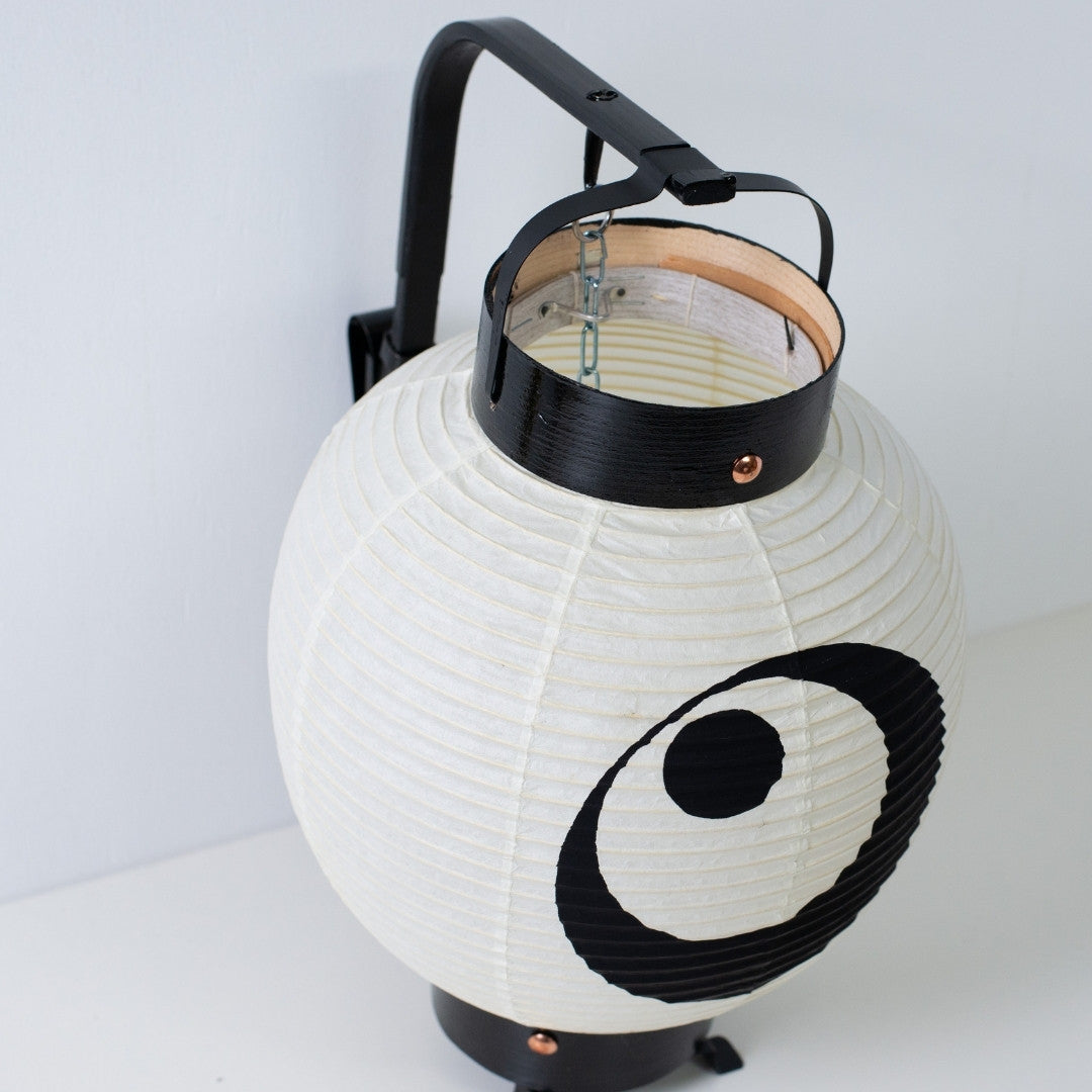 High angle view of a small Japanese lantern showing the internal bamboo bow structure and black lacquered wood frames.
