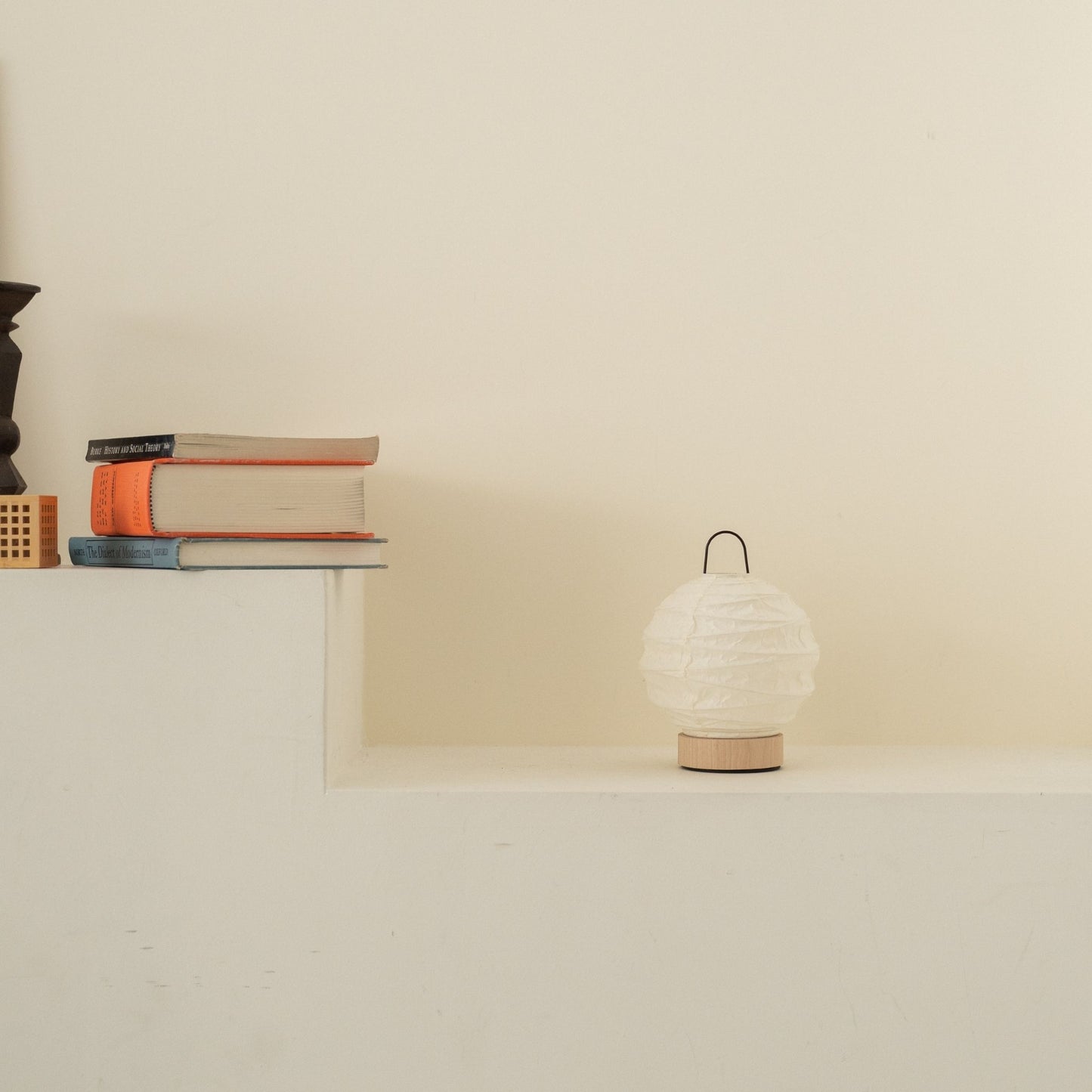 Unlit round Japanese paper table lamp "Yuhi" placed on a white console table in a minimalist Japandi living room.