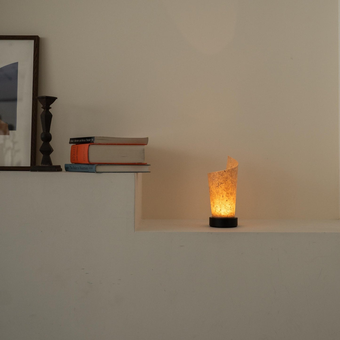 Lit Japanese paper table lamp "Maki" Cedar Bark glowing warmly as an ambient lamp on a white console table in a Japandi living room.
