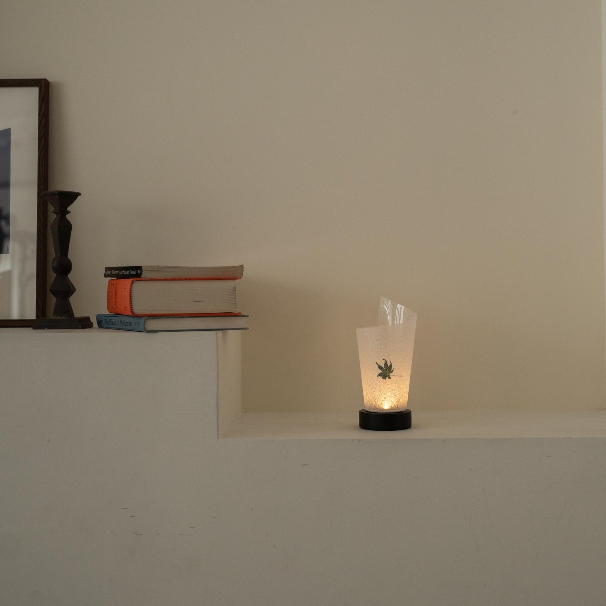 Lit Japanese paper table lamp "Maki" Momiji Leaf glowing warmly as an ambient lamp on a white console table in a Japandi living room.
