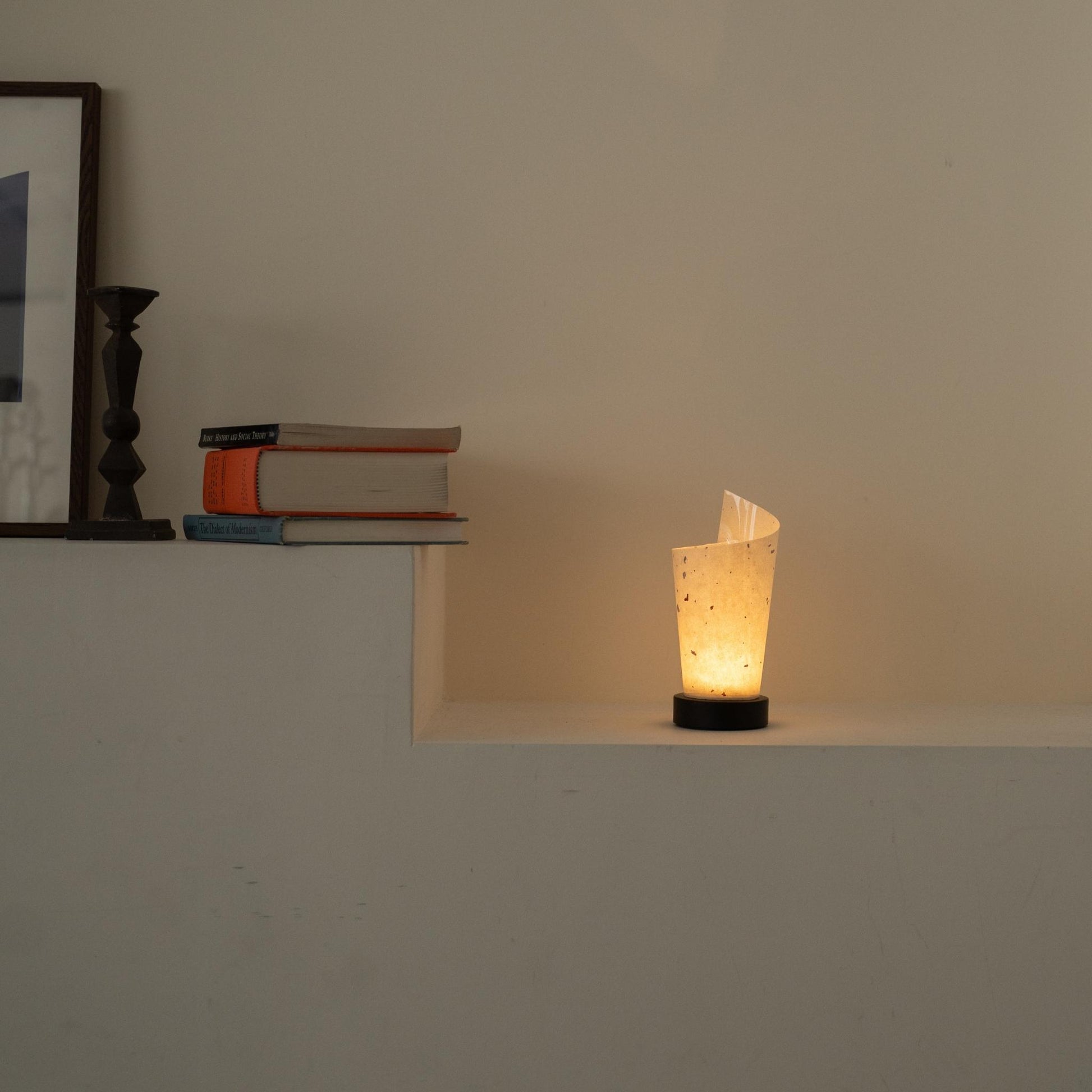 Lit Japanese paper table lamp "Maki" glowing warmly as an ambient lamp on a white console table in a Japandi living room.