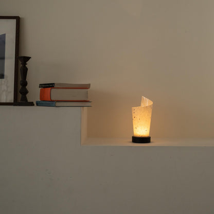 Lit Japanese paper table lamp "Maki" glowing warmly as an ambient lamp on a white console table in a Japandi living room.