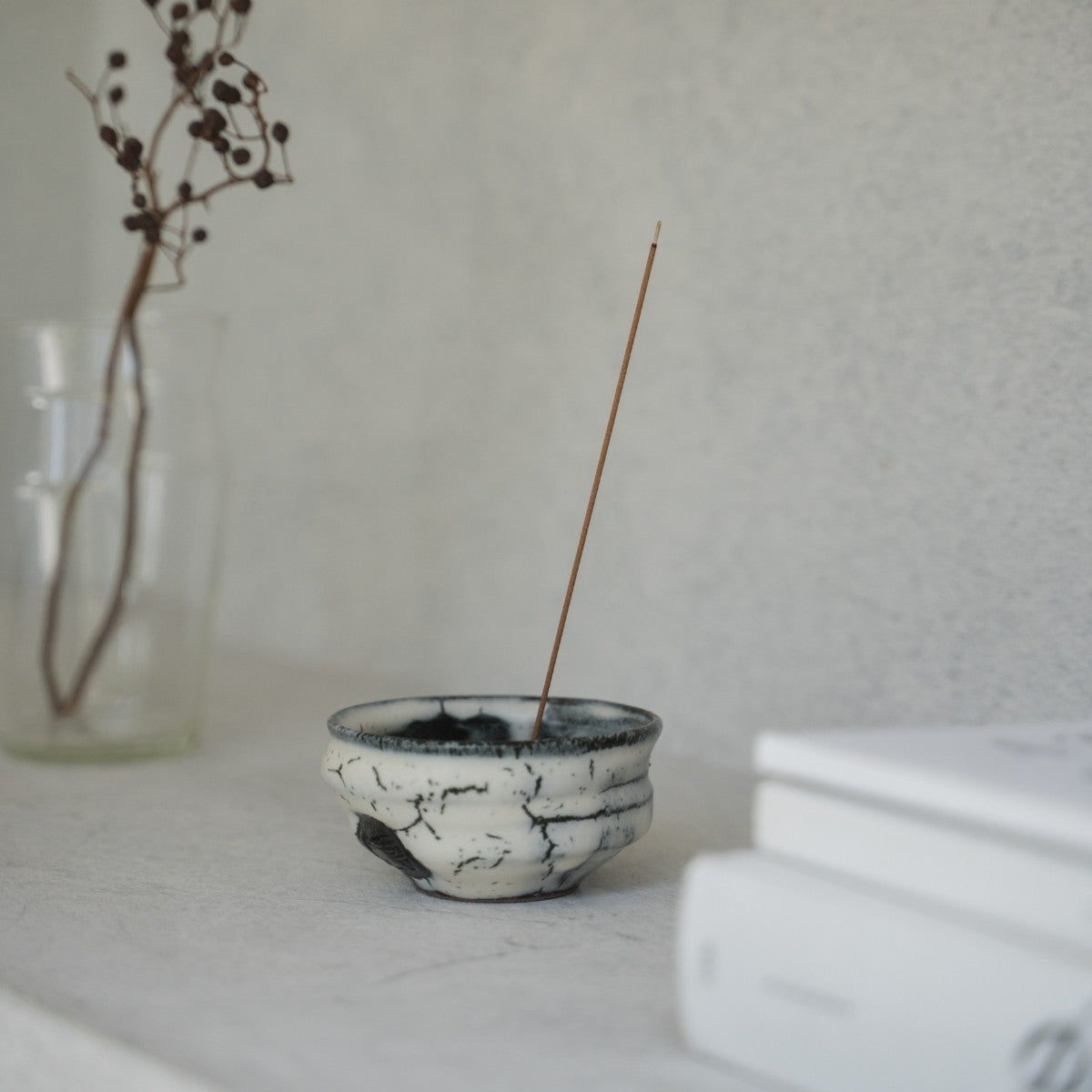 White and black deep bowl Japanese incense burner with gold and black glazes on a bright shelf, adding wabi-sabi to a Japandi living room.