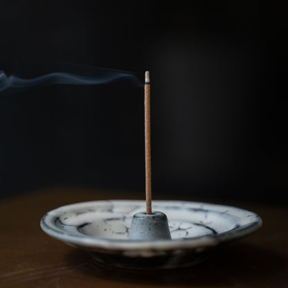 White and grey Japanese incense holder on a wooden table with drifting smoke, creating serenity for mindful meditation.