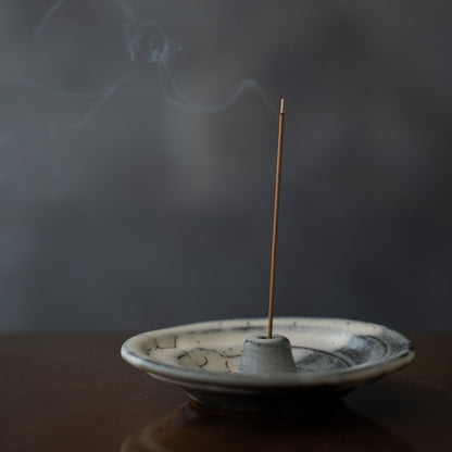 Cloud glazed Japanese incense holder on a dark table with swirling smoke, enhancing focus during a morning yoga practice.