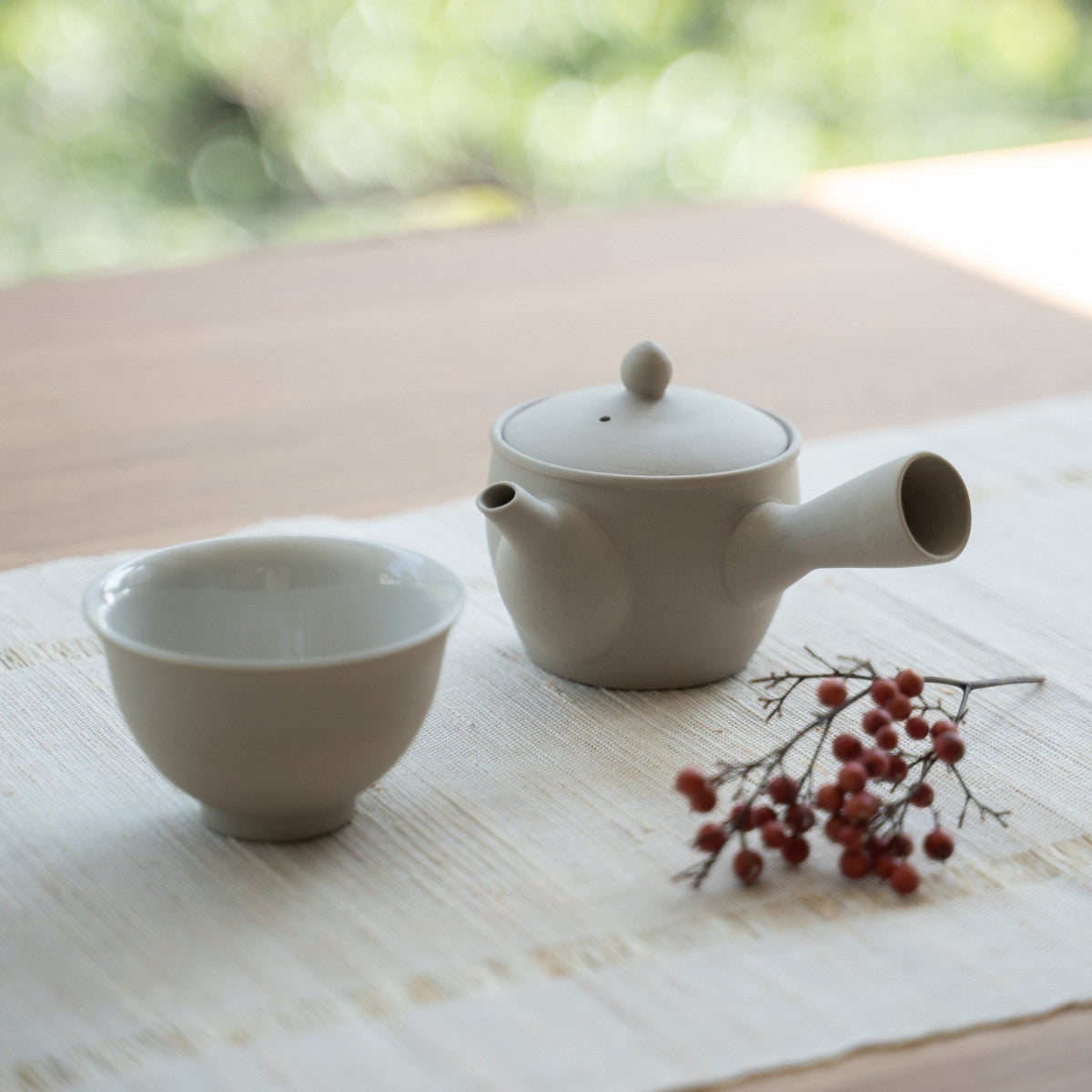 Hvid japansk tekande "Fuyo" og en japansk tekop på en linnedmåtte til teelskere, der forbereder et roligt dagligt ritual.