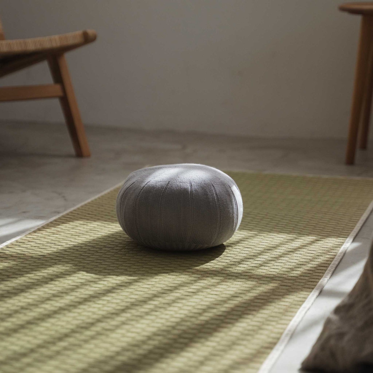 Lagoon gray zafu meditation cushion positioned on a tatami mat illuminated by natural window light.